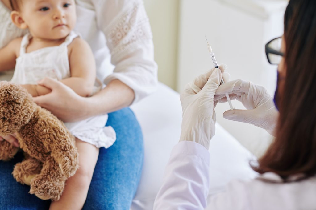 Un médico dispuesto a inyectar una vacuna en el brazo a una niña