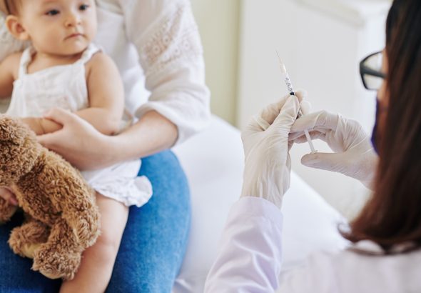 Un médico dispuesto a inyectar una vacuna en el brazo a una niña