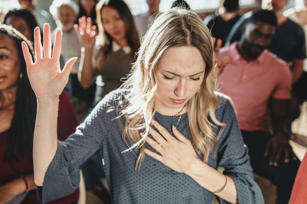 Mujer levantando la mano en señal de oración. (Imagen ilustrativa)