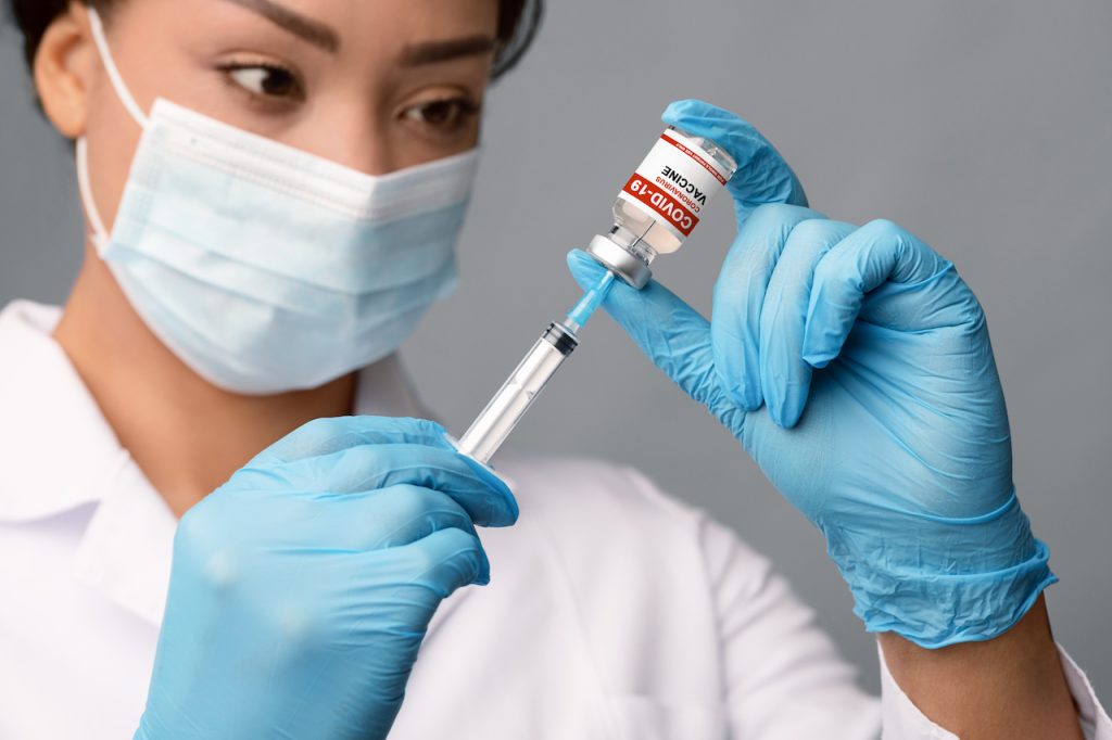Vacunación Covid-19. Doctora llenando jeringa con medicamento inyectable